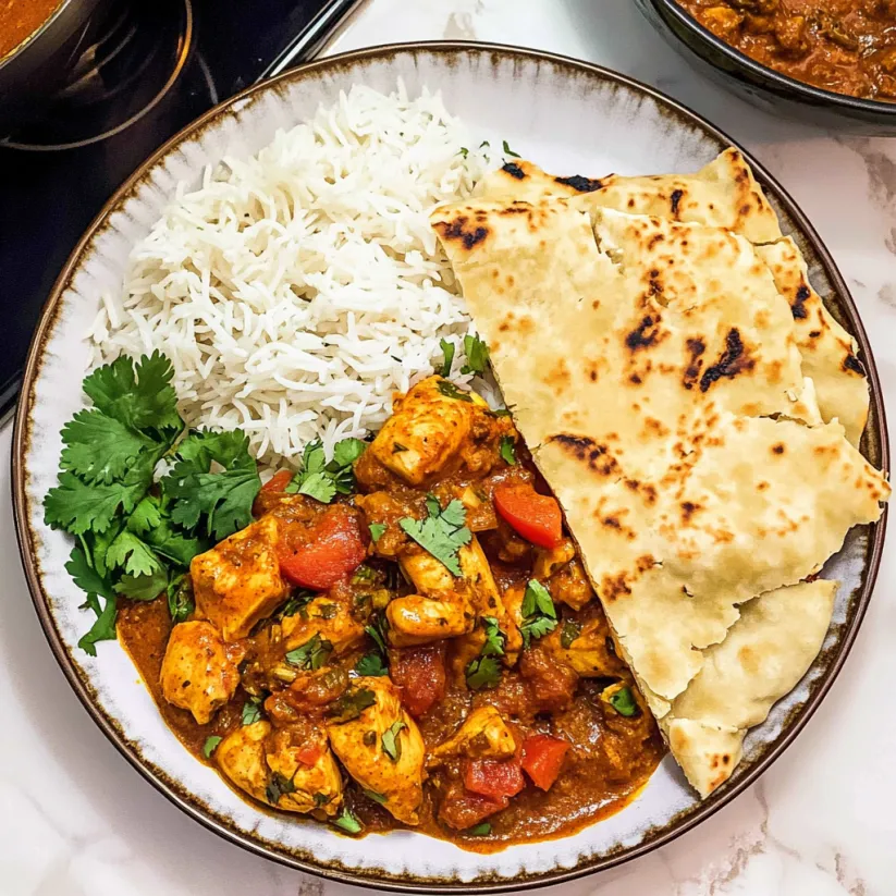 A plate of food with rice, chicken, and tomatoes.