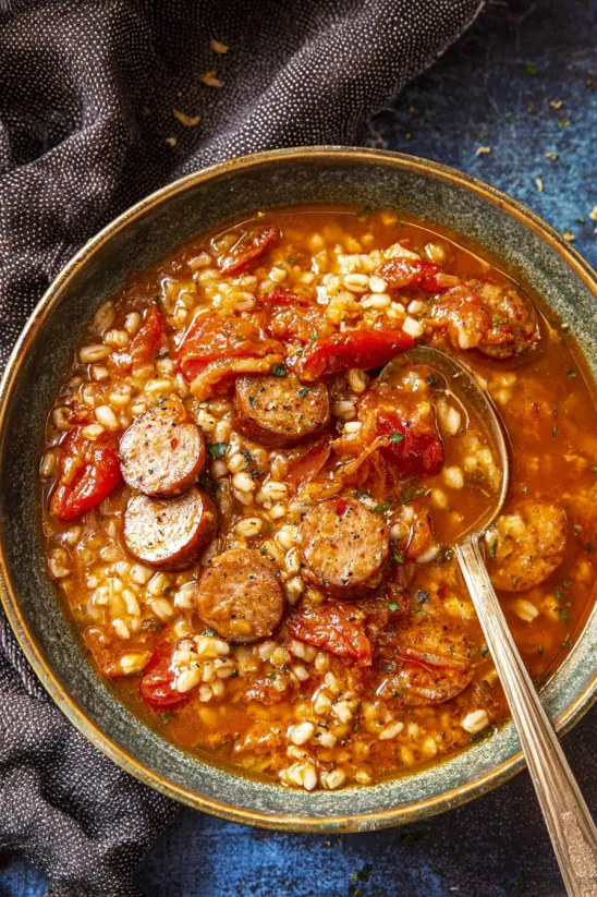 A bowl of jambalaya soup with sausage and tomatoes.