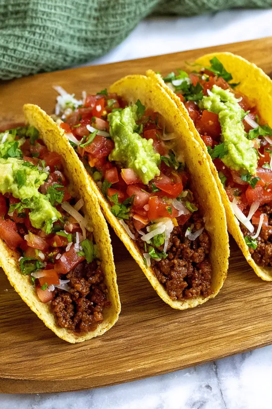 Two tacos with meat and tomatoes.