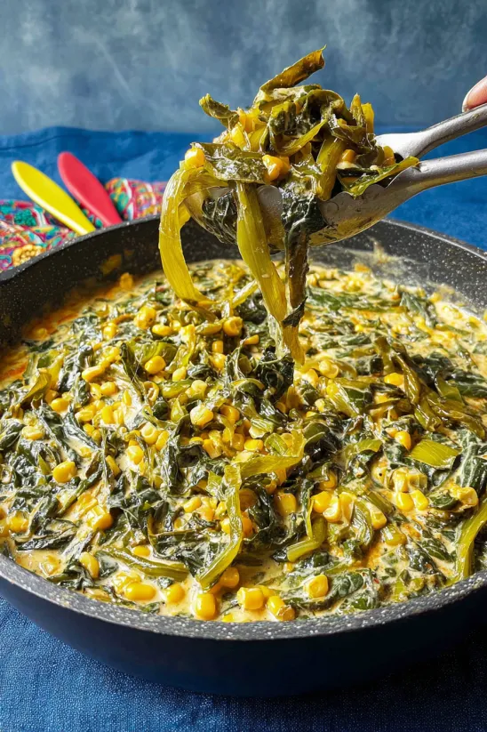 A spoon is scooping up food from a pan.