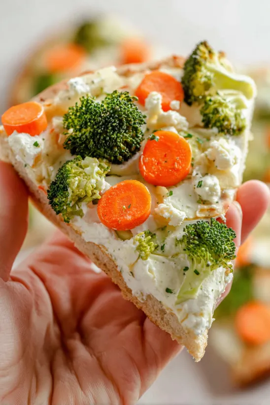 A slice of pizza with broccoli and carrots on it.