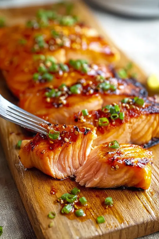A piece of grilled salmon with a honey-sriracha sauce.