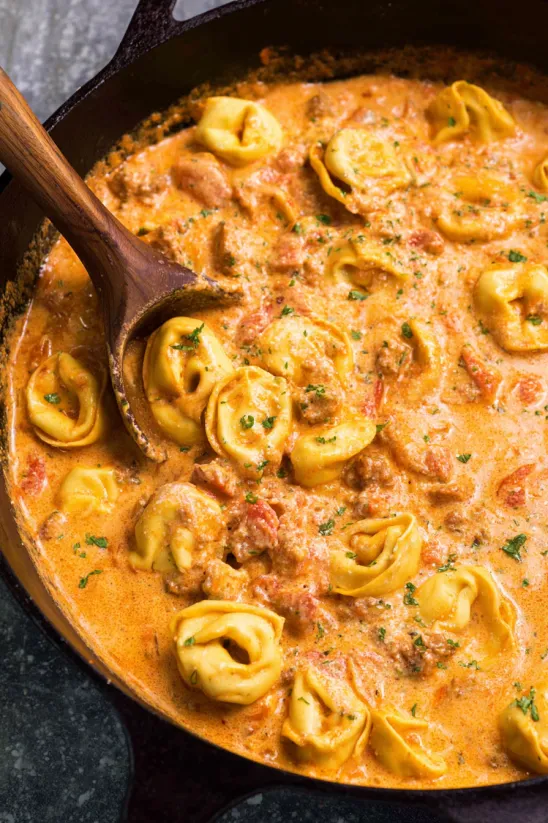 A bowl of creamy tortellini pasta with fire roasted tomatoes.