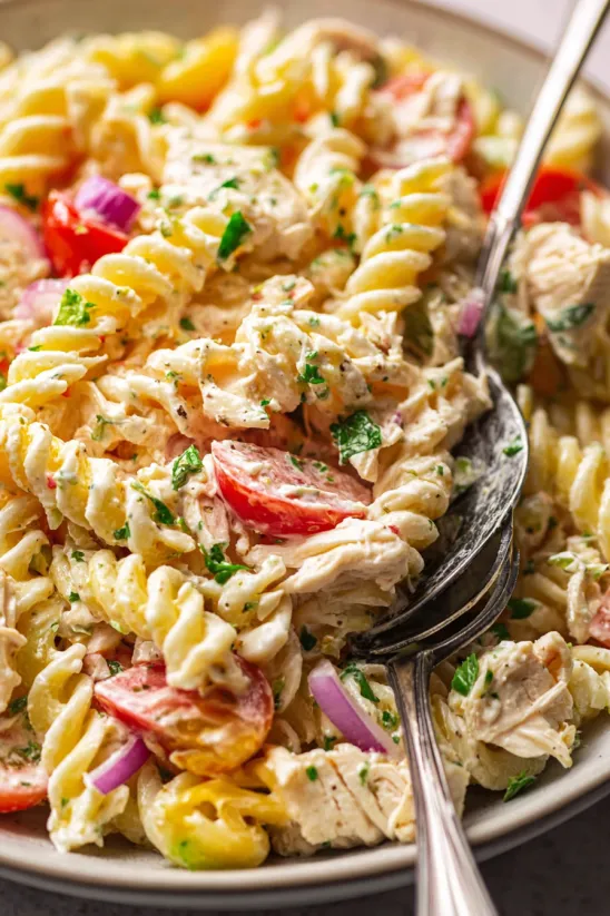 A fork is stuck in a bowl of tuna pasta salad.
