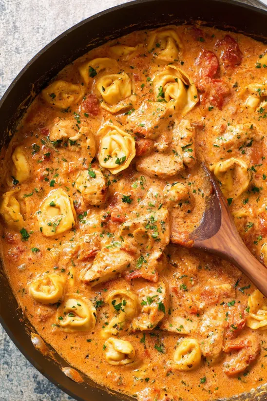 A pan of food with a wooden spoon in it.