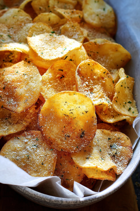 A bowl of chips with parsley on top.