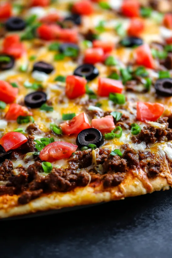 A pizza with tomatoes, olives, and cheese.