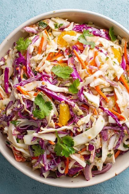 A bowl of salad with carrots, cabbage, and other vegetables.