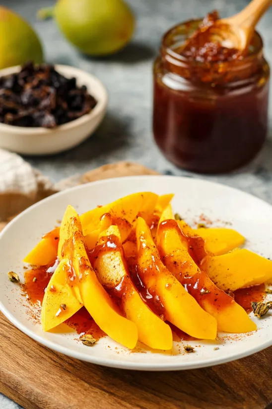 A plate of sliced mango with a sauce on it.