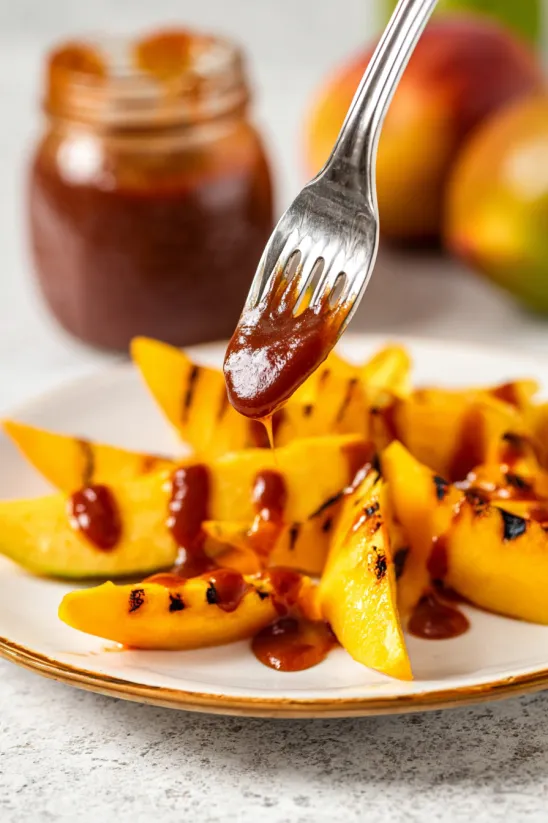 A plate of sliced peaches with sauce drizzled over them.