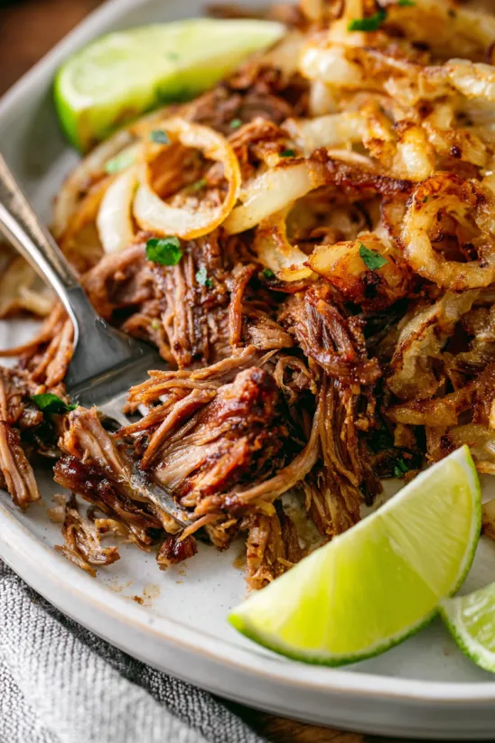 A plate of food with a fork and a lime.