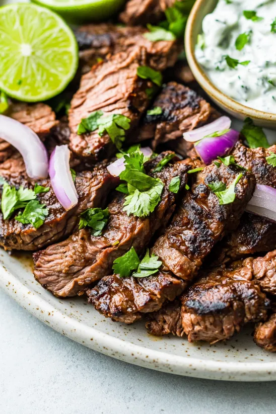 A plate of meat with onions and lime.