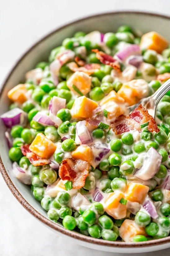 A bowl of food with peas and bacon.