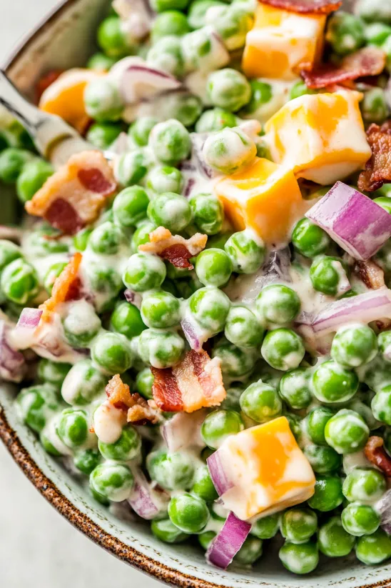 A bowl of peas with bacon and cheese.