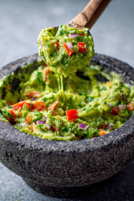 A bowl of guacamole with a spoon in it.