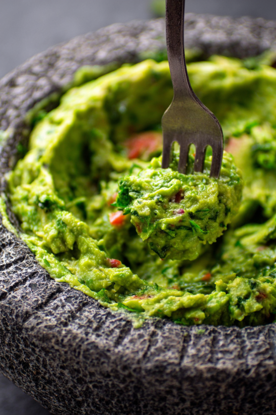 A fork is in a bowl of guacamole.