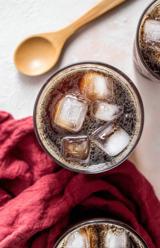 A glass of Carajillo with ice and a spoon.