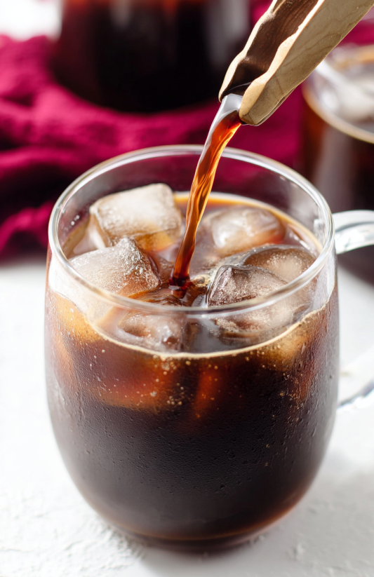 A glass of soda with ice and a straw.