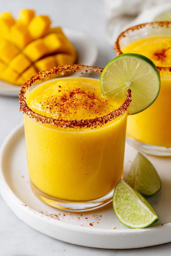 A glass of frozen mango margarita with a lime wedge on the side.