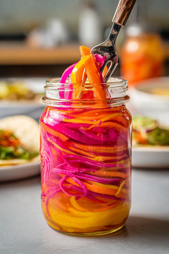 A jar of pickles with a spoon in it.