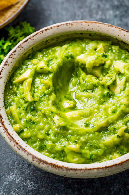 A bowl of green salsa with chunks of avocado.