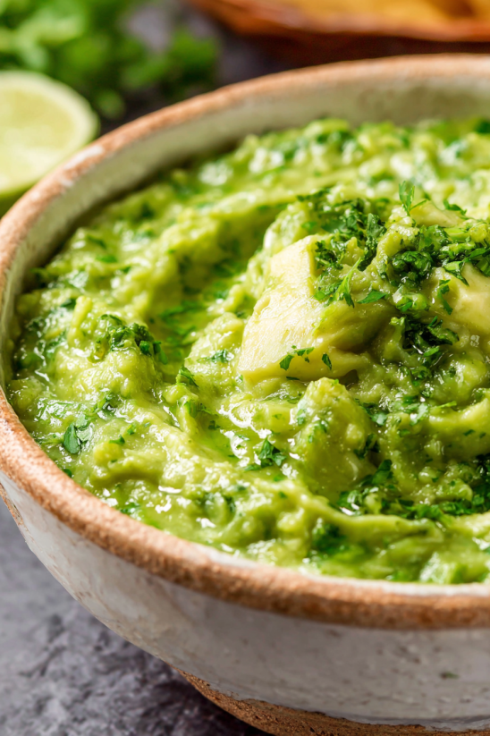 A bowl of green soup with avocado.