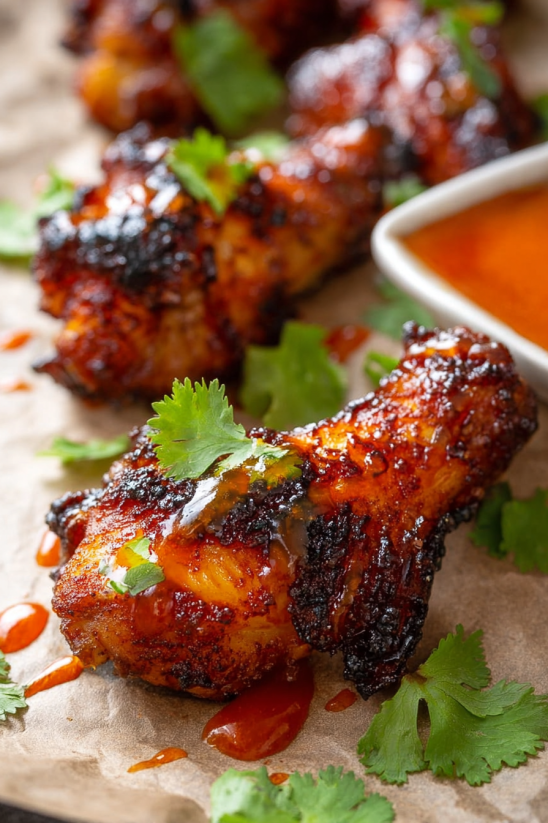 A bowl of sauce with chicken wings.