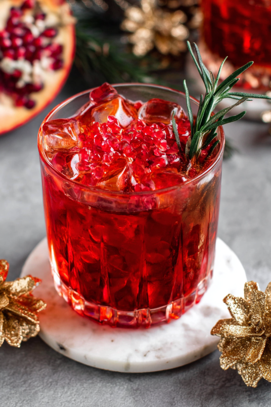 A glass of red liquid with a sprig of mint on top.