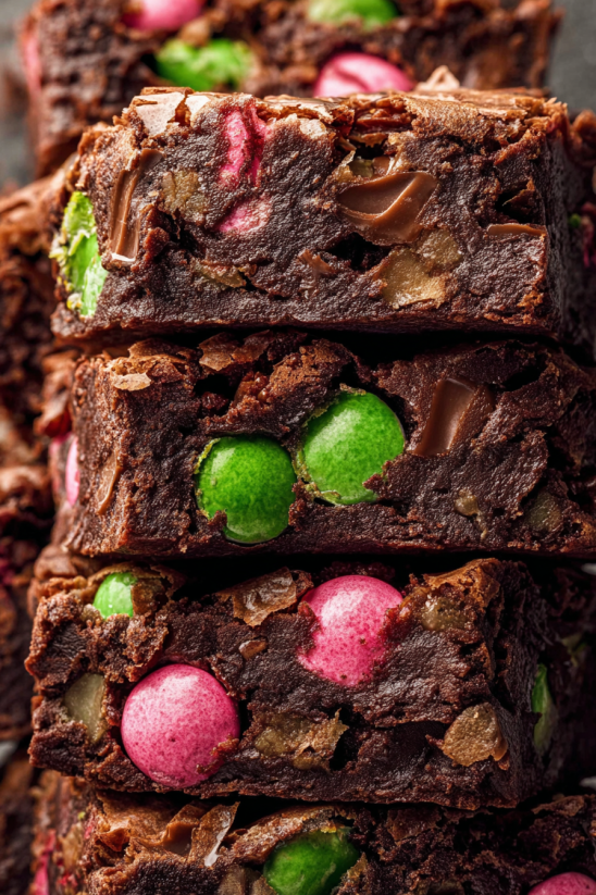 Three pieces of chocolate cake with green and pink candy on top.