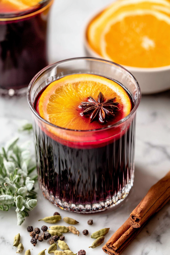 A glass of red wine with an orange slice on top.