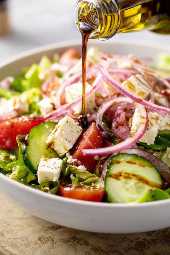 A bowl of Greek salad with tomatoes, cucumbers, onions, and feta cheese.