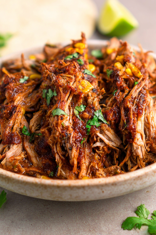 A bowl of meat with corn on the cob.