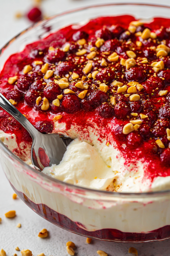 A bowl of cranberry jello salad with cream cheese topping.