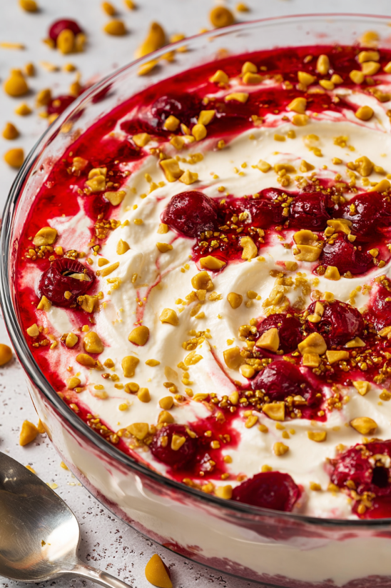 A bowl of red raspberry yogurt with nuts on top.