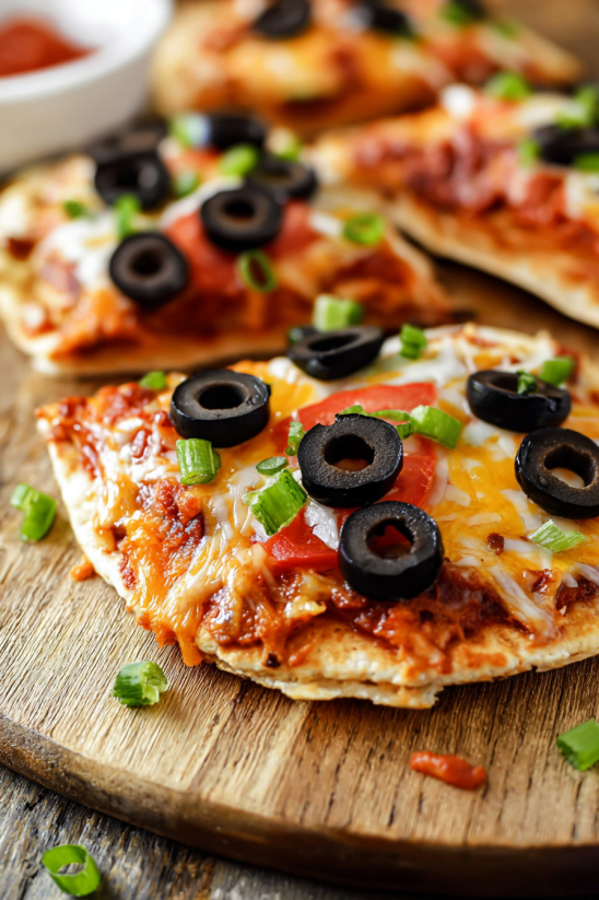 A slice of Mexican pizza with black olives and tomatoes.