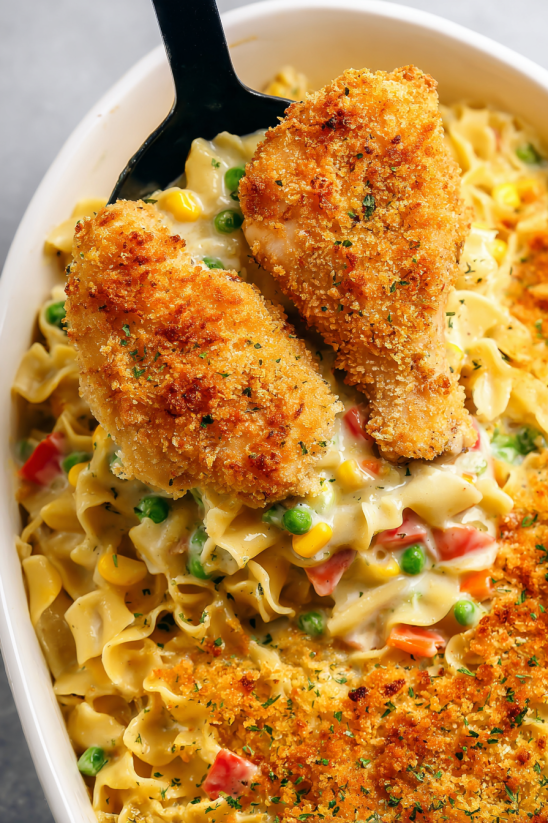 A dish of chicken noodle bake with peas and corn.
