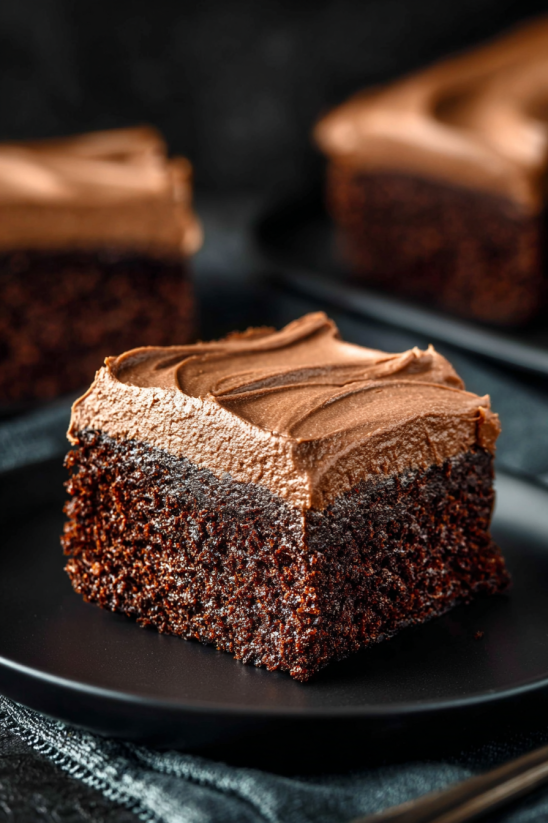 A slice of chocolate mayonnaise cake on a black plate.