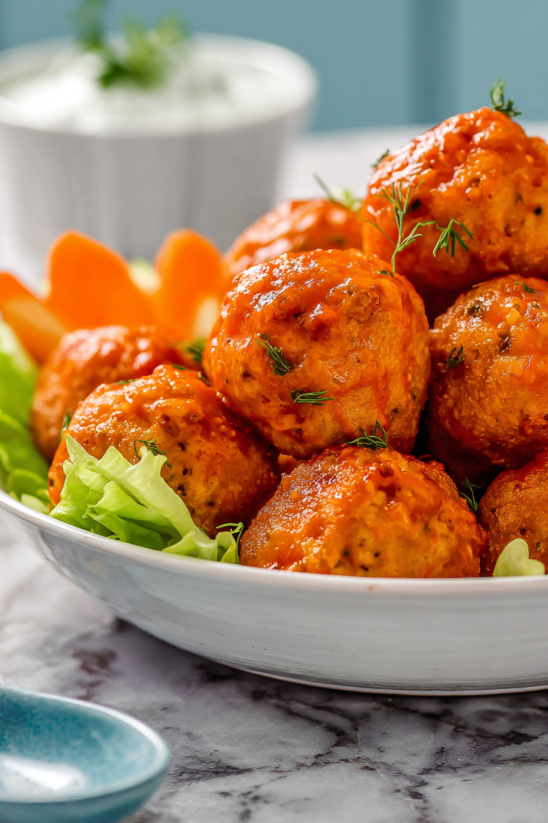 A bowl of meatballs with a carrot.