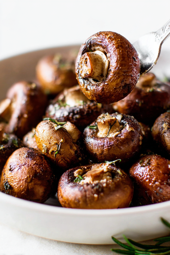 A bowl of mushrooms being scooped into a spoon.
