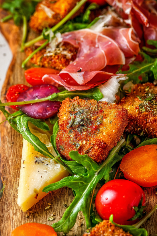 A Christmas charcuterie board with cheese, meat, and vegetables.