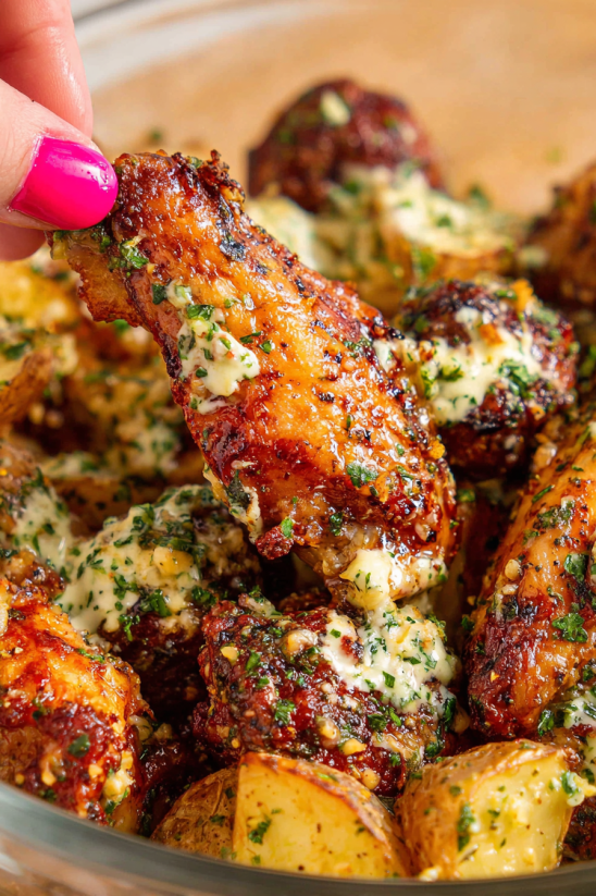 A hand holding a piece of garlic Parmesan crispy air fried chicken wing.