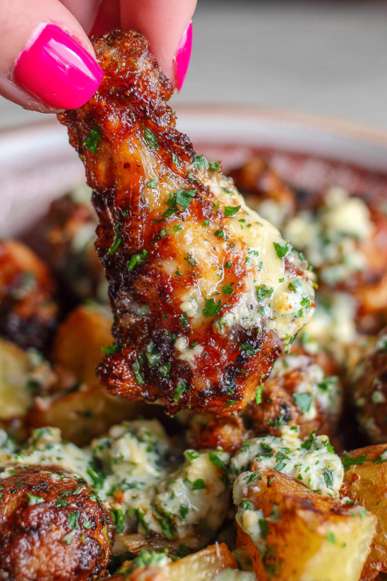 A hand holding a piece of garlic Parmesan crispy air fried chicken wing.
