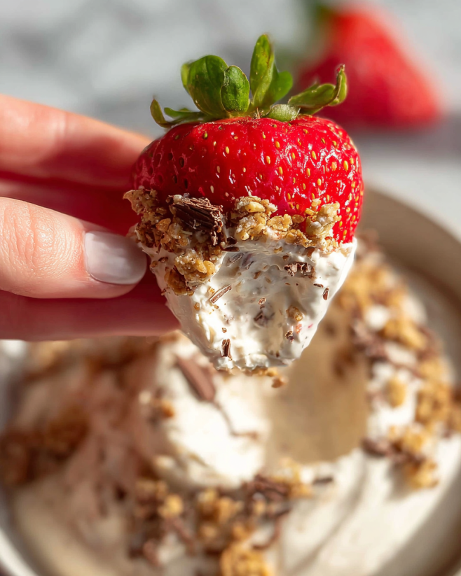 A hand holding a piece of strawberry ice cream.
