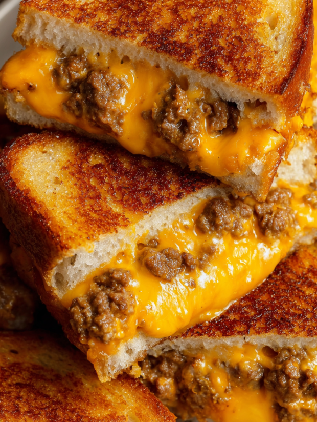 A stack of grilled cheese sandwiches with sausage and egg.