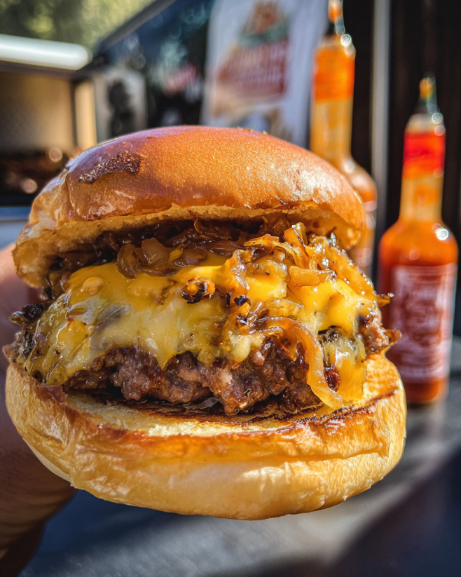 A person is holding a smoked Cajun burger.