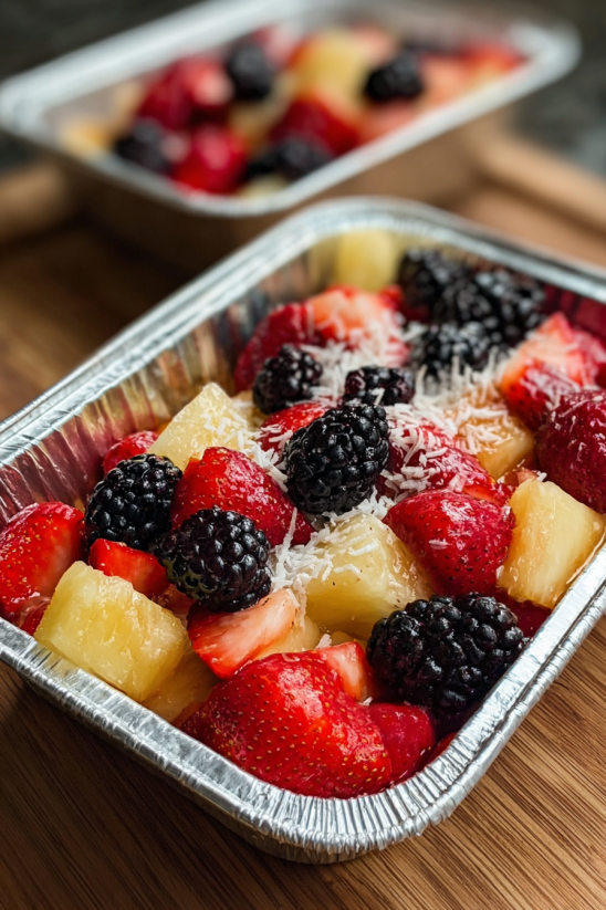 A fruit salad in a tin foil tray.