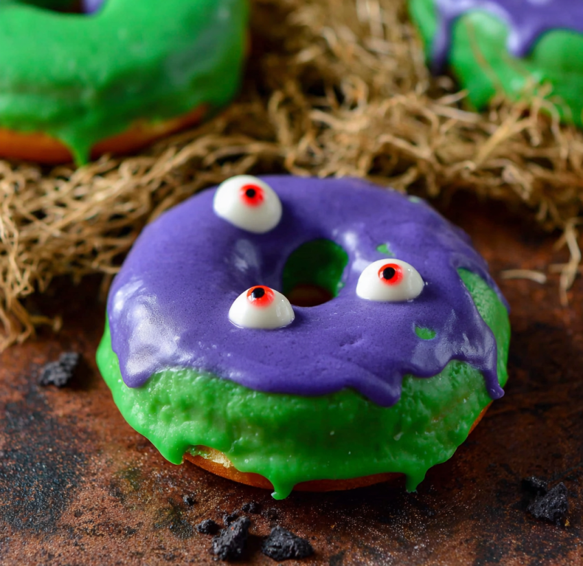 A green donut with purple frosting and two red eyes.