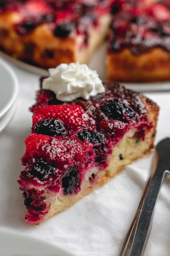 A slice of blueberry cake with whipped cream on top.