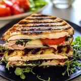 A sandwich with tomatoes and greens on top.
