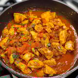 A pan of chicken with tomatoes and spices.